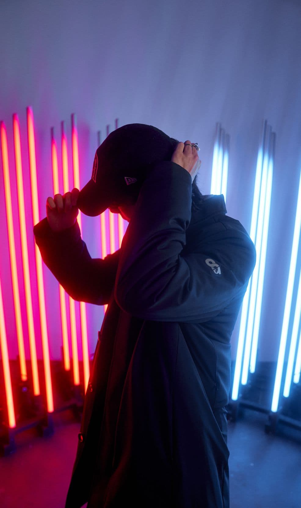 Person from behind wearing a jacket in front of vertical LED light tubes